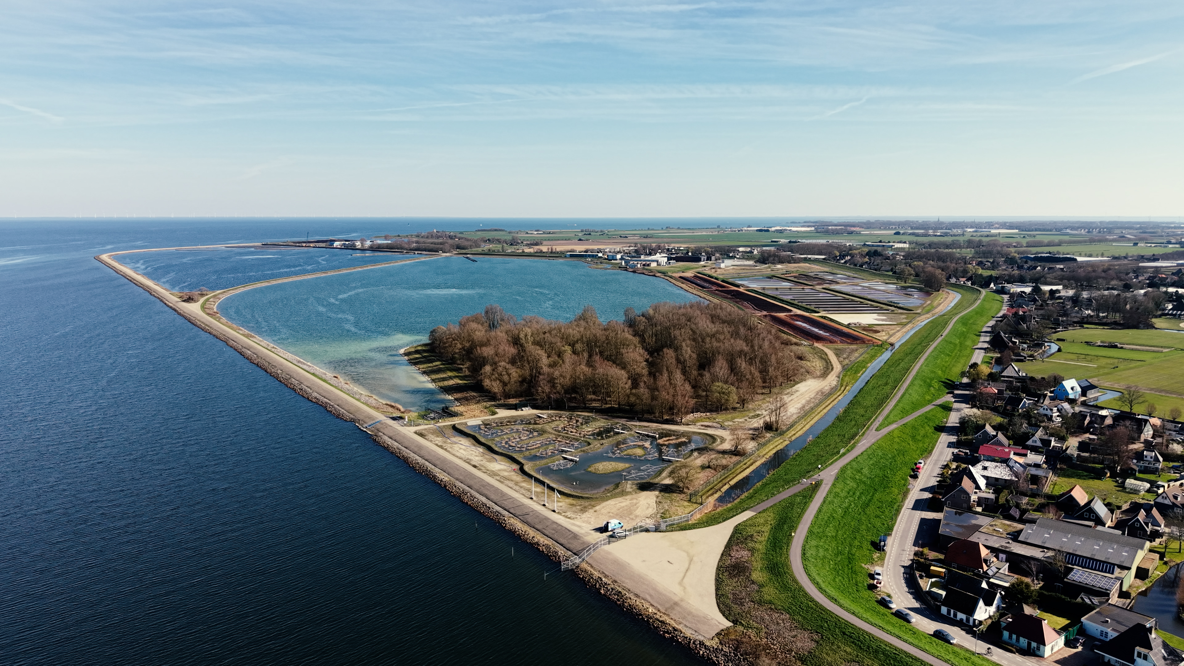 Luchtfoto van Andijk waar het bekken, de proeflocatie, de dijk en het dorp aan elkaar grenzen